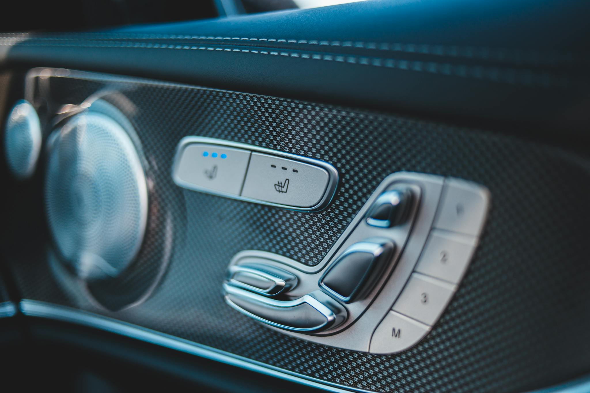 Close-up of a car's seat adjustment and speaker details, showcasing contemporary design.
