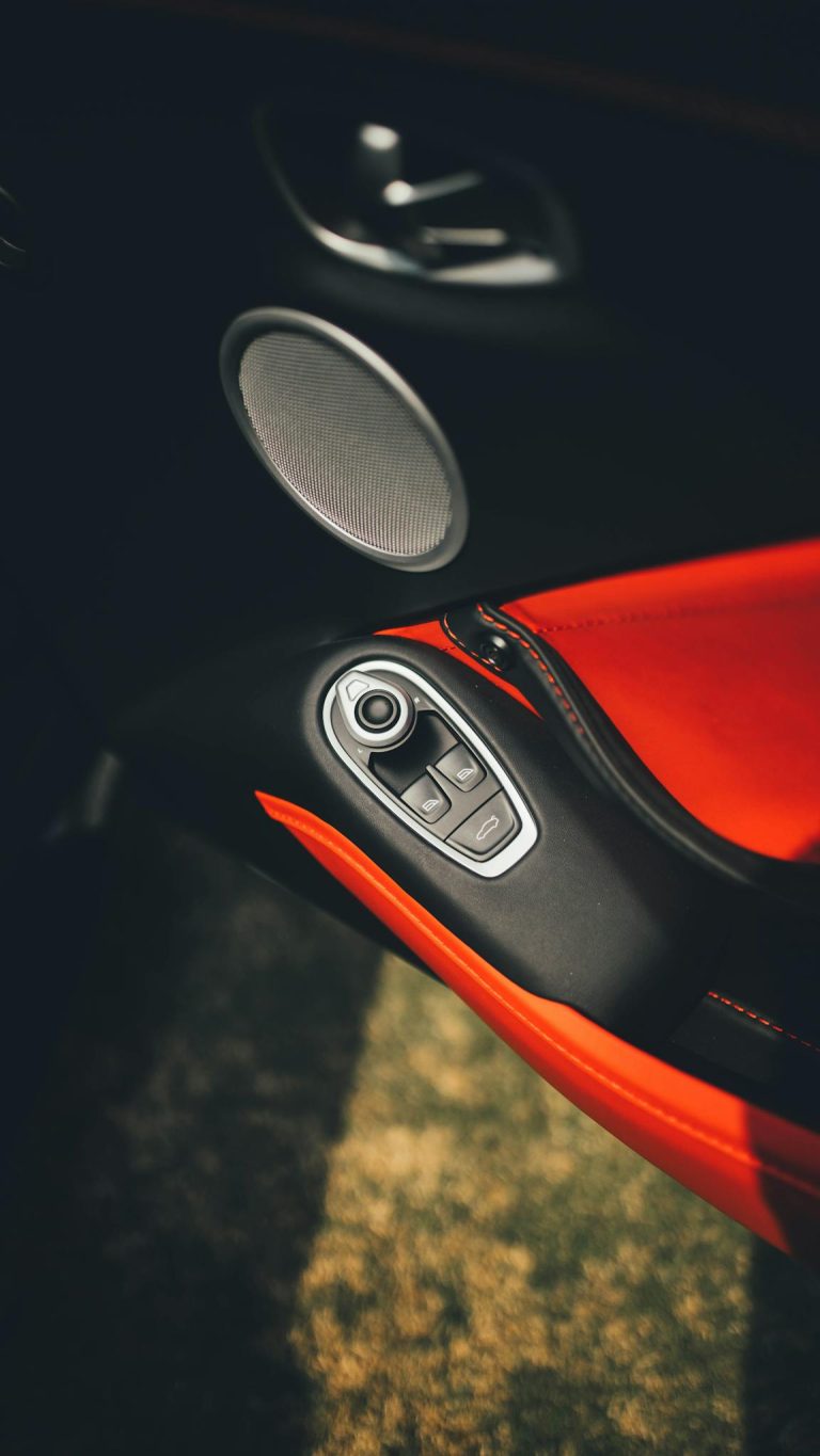 Close-up of a luxury car's red leather interior with a prominent speaker and controls.