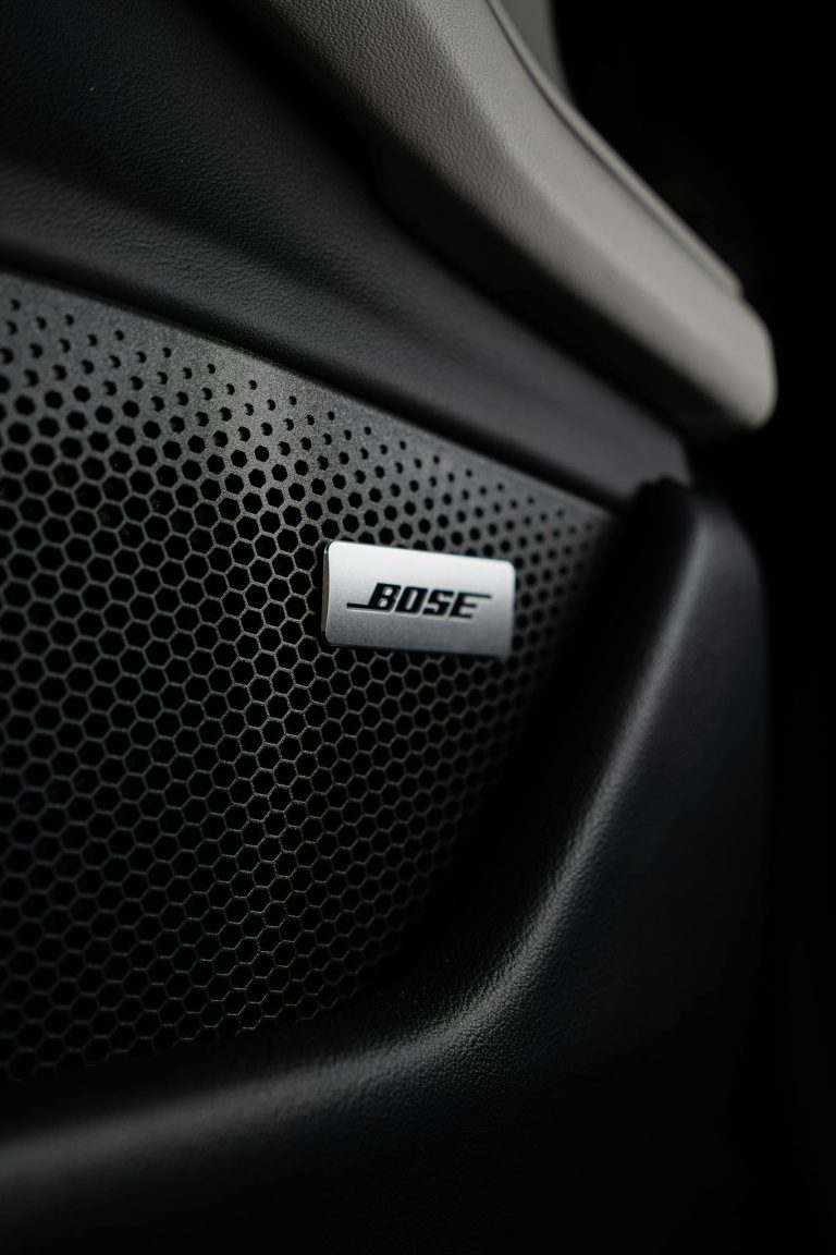 Detailed view of a Bose speaker integrated into a car's black leather interior.
